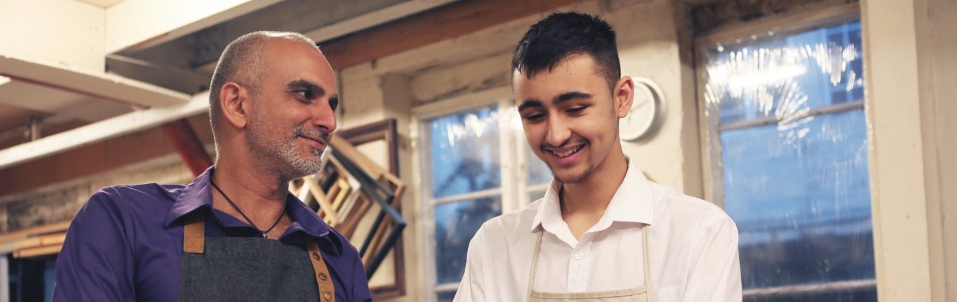 Craftsman and apprentice talking in a workshop