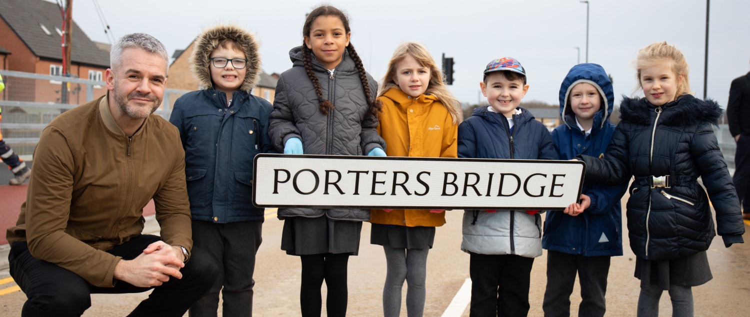 Mayor Coppard with schoolchildren, holding a road sign saying Porters Bridge.