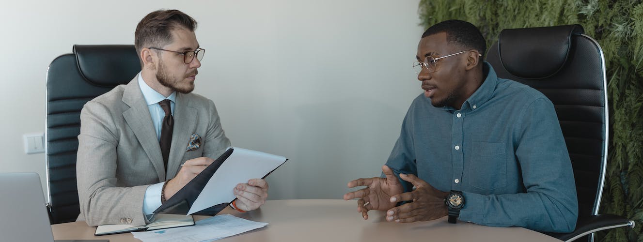Two men sitting on a table and exchanging Information